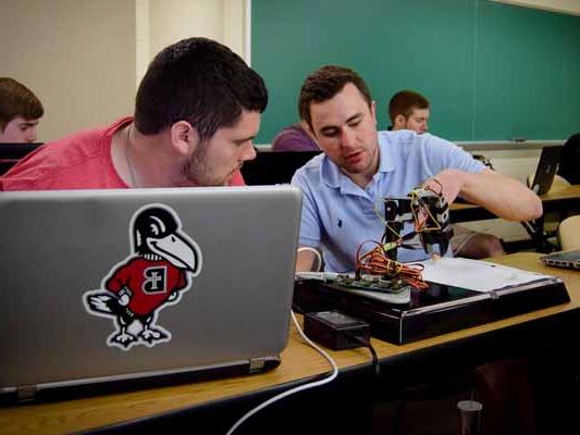 Students working with a robotic arm in engineering class