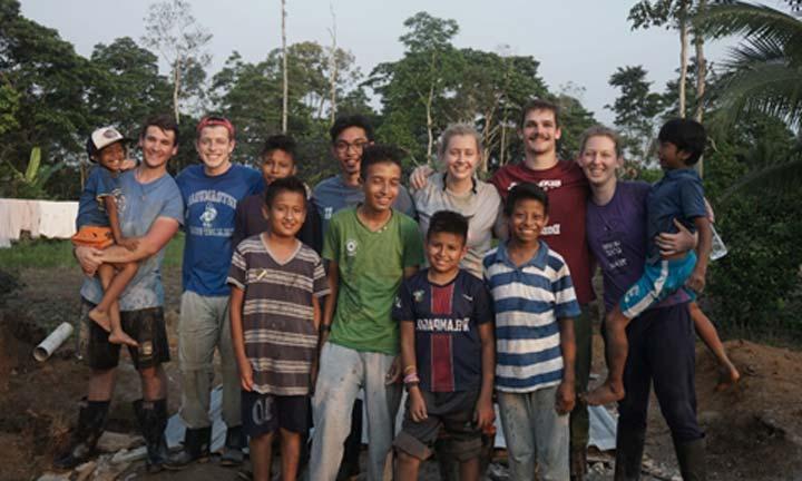 Students pose with children while on a mission trip